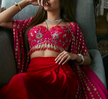 Esha Gupta in Arpita Mehta Collection | Esha Gupta in luxurious ruby red cape with linear hand embroidery paired with a ruby red tulip skirt and lotus and pineflower embroidered blouse with fringe detailing.