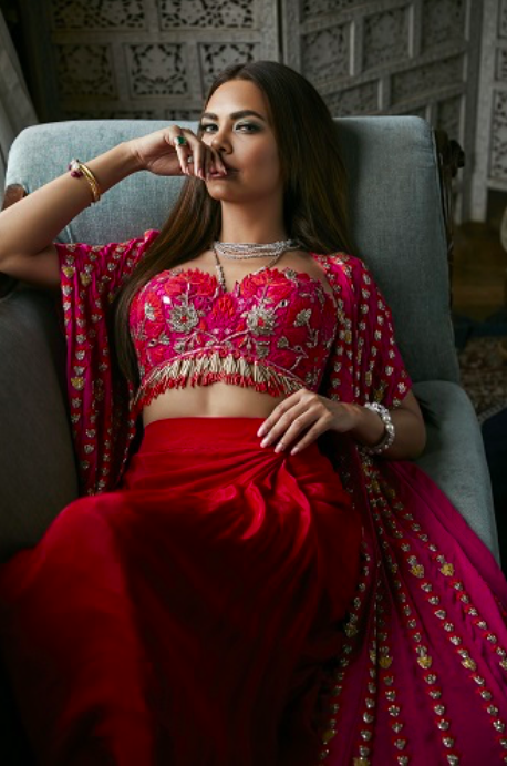Esha Gupta in Arpita Mehta Collection | Esha Gupta in luxurious ruby red cape with linear hand embroidery paired with a ruby red tulip skirt and lotus and pineflower embroidered blouse with fringe detailing. 